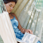 Young woman reading book in hammock